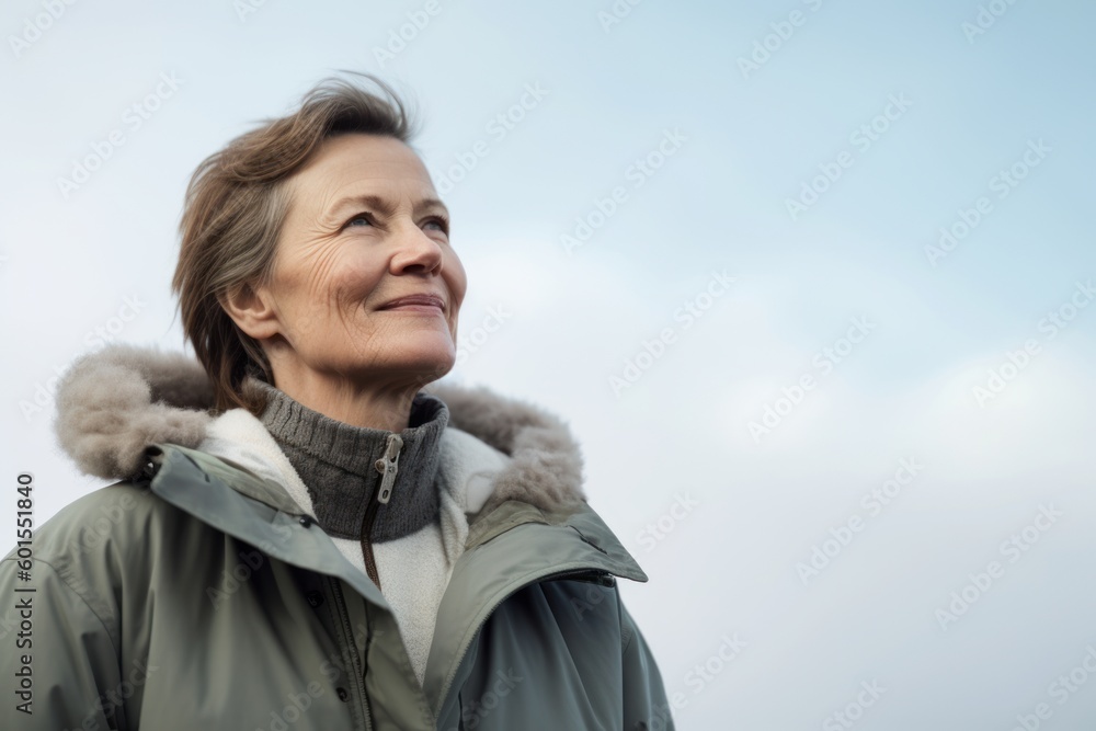 Portrait of a smiling senior woman in winter jacket against blue sky Portrait of a smiling senior woman in winter jacket against blue sky