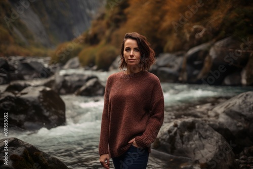 Portrait of a young woman in a sweater on the background of a mountain river.