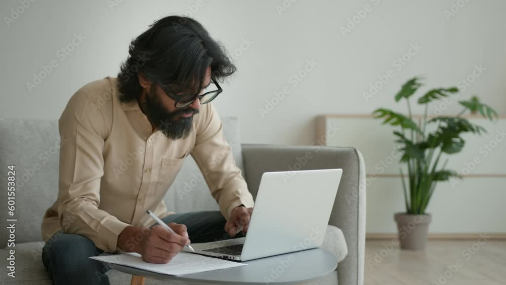 Arabian Indian muslim man guy businessman write notes papers paperwork writing statement document male accountant pay credit taxes utility bills online at home work laptop check data budget e-commerce Arabian Indian muslim man guy businessman write notes papers paperwork writing statement document male accountant pay credit taxes utility bills online at home work laptop check data budget e-commerce