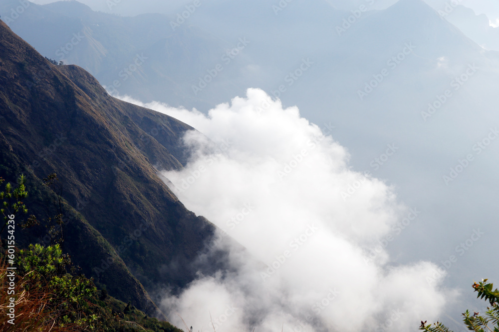 beautiful tall rock mountain top view with clouds under in munnar, kerala india