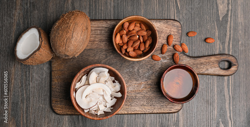 Tasty coconut, chips, almond nuts and oil on wooden background, top view