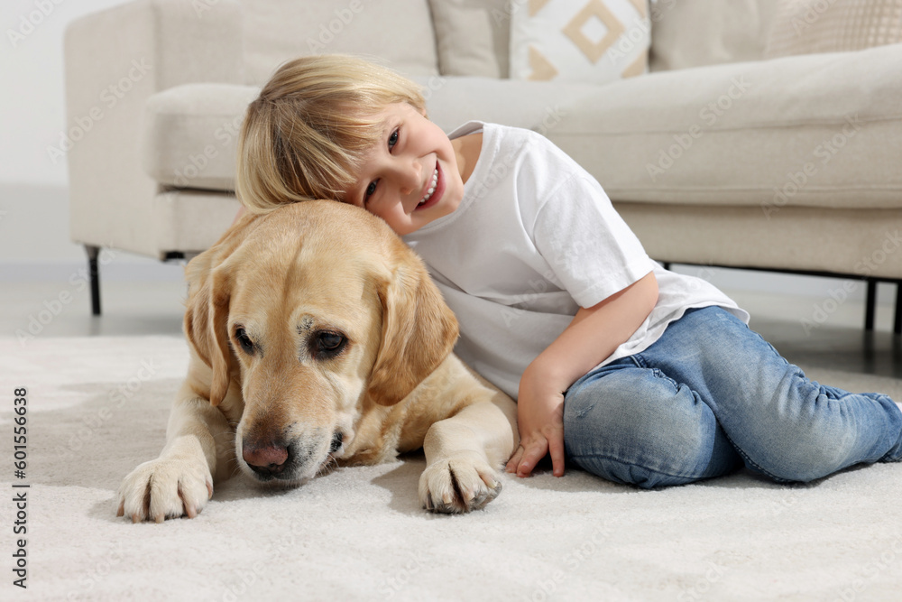 Cute little child with Golden Retriever on floor at home. Adorable pet