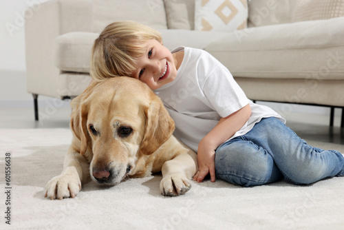 Cute little child with Golden Retriever on floor at home. Adorable pet