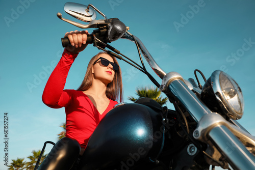 Beautiful young woman riding motorcycle on sunny day, low angle view