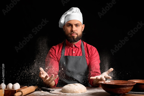 Male baker sprinkling dough...