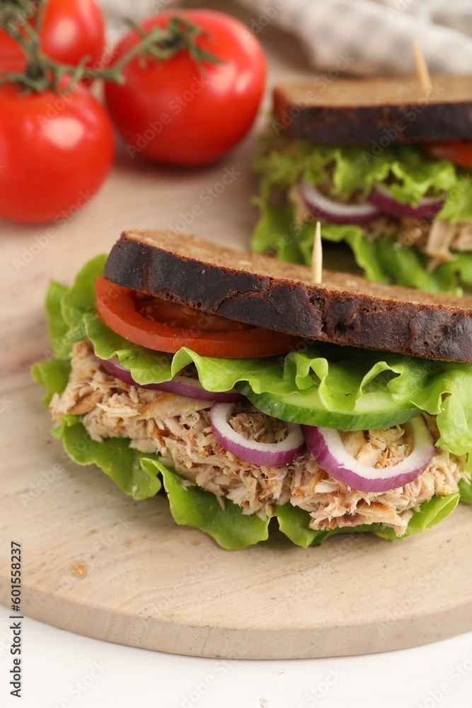 Delicious sandwiches with tuna and vegetables on wooden serving board, closeup