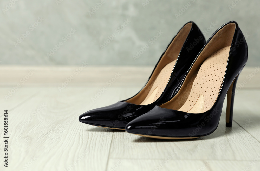 Orthopedic insoles in high heel shoes on floor, closeup. Space for text Orthopedic insoles in high heel shoes on floor, closeup. Space for text