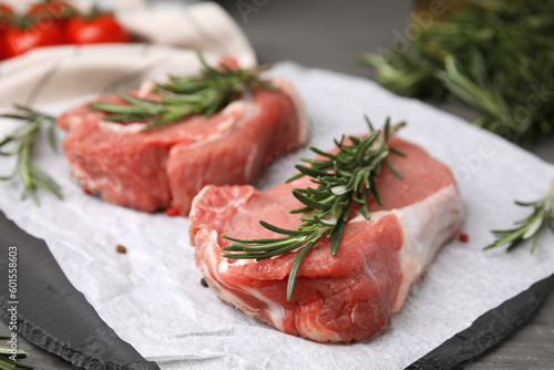 Fresh raw meat with rosemary on slate plate, closeup