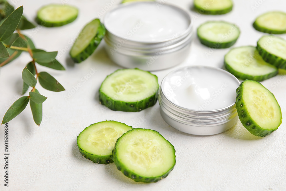 Jars of natural cream and cucumber slices on light background, closeup Jars of natural cream and cucumber slices on light background, closeup