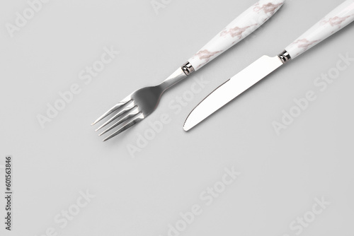 Stainless steel fork and knife with plastic handle on grey background