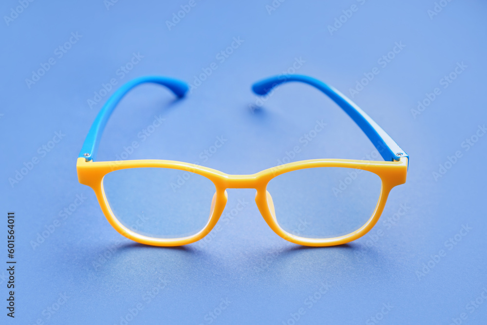 Fototapeta premium Stylish yellow eyeglasses on blue background