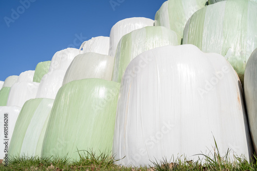 Wrapped and stacked bales of hay with blue sunny sky in the background