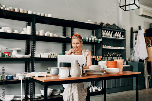Creative, pottery and woman sitting with laptop in workshop. Small business or startup, technology or social networking and female person in kitchen with art sculpture on the table or on desk