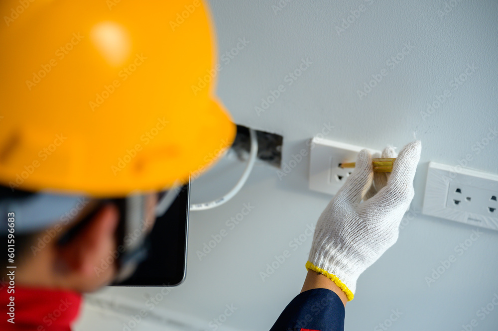 An electrician is testing electrical power and installing electrical switches in homes and building panel breakers. An electrician is testing electrical power and installing electrical switches in homes and building panel breakers.