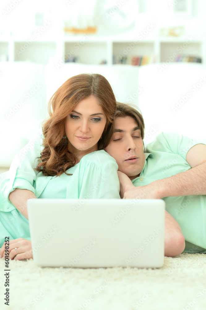 Happy young couple looking at laptop at home Happy young couple looking at laptop at home
