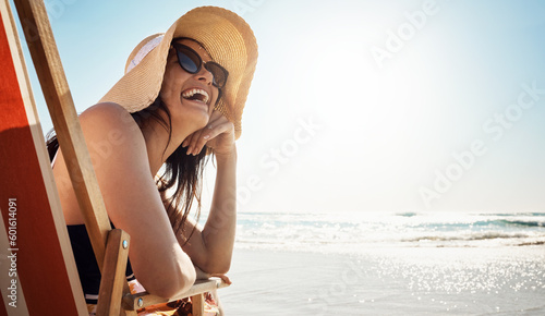Beach, summer and mockup with a woman laughing while sitting on a chair by the ocean or sea on vacation. Blue sky, view and horizon over water with an attractive young female tourist feeling happy