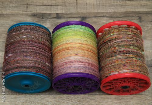 Photography Closeup detail of a bobbin full of colourful organic natural handspun and handdyed merino sheep wool yarn , spun on a traditional spinning wheel