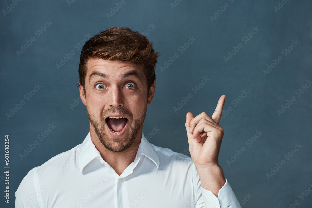 Portrait, wow and idea with a man pointing in studio on a blue background during a lightbulb moment. Face, surprise and eureka with an excited young male person looking shocked or amazed by good news Portrait, wow and idea with a man pointing in studio on a blue background during a lightbulb moment. Face, surprise and eureka with an excited young male person looking shocked or amazed by good news