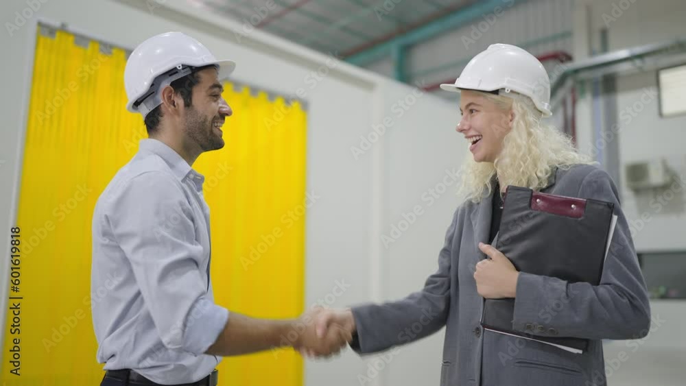 Hispanic latin engineer man come in at warehouse for meeting with caucasian woman manager shaking hands for geeting while working at factory warehouse Hispanic latin engineer man come in at warehouse for meeting with caucasian woman manager shaking hands for geeting while working at factory warehouse