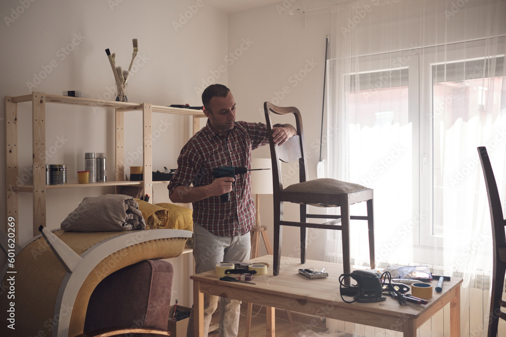 Man working in a small home workshop for furniture repairing and restoration. Man working in a small home workshop for furniture repairing and restoration.