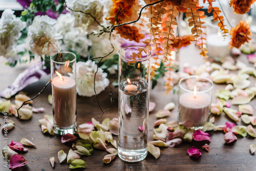 Candles, rose petals on floor. Closeup decor detail. Photo wall, arch decorated pink, orange flower for birthday party in banquet area, hall. Wedding reception for luxury ceremony. Decoration of event Candles, rose petals on floor. Closeup decor detail. Photo wall, arch decorated pink, orange flower for birthday party in banquet area, hall. Wedding reception for luxury ceremony. Decoration of event