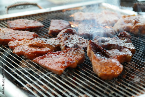 Seasoned pork ribs being grilled on a charcoal brazier