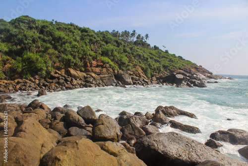 The seashore of Unawatuna, Sri Lanka dotted with palm trees. Blue sky with copy space for text