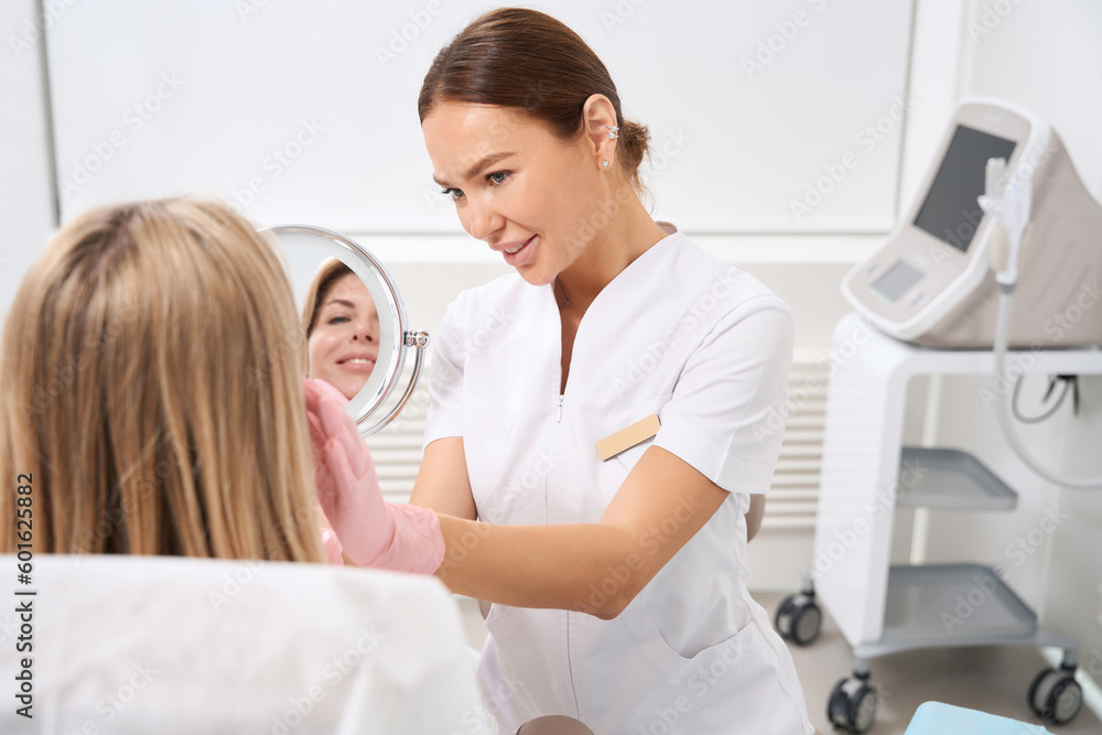 Cosmetologist in clinic of aesthetic medicine consults patient in bathrobe Cosmetologist in clinic of aesthetic medicine consults patient in bathrobe