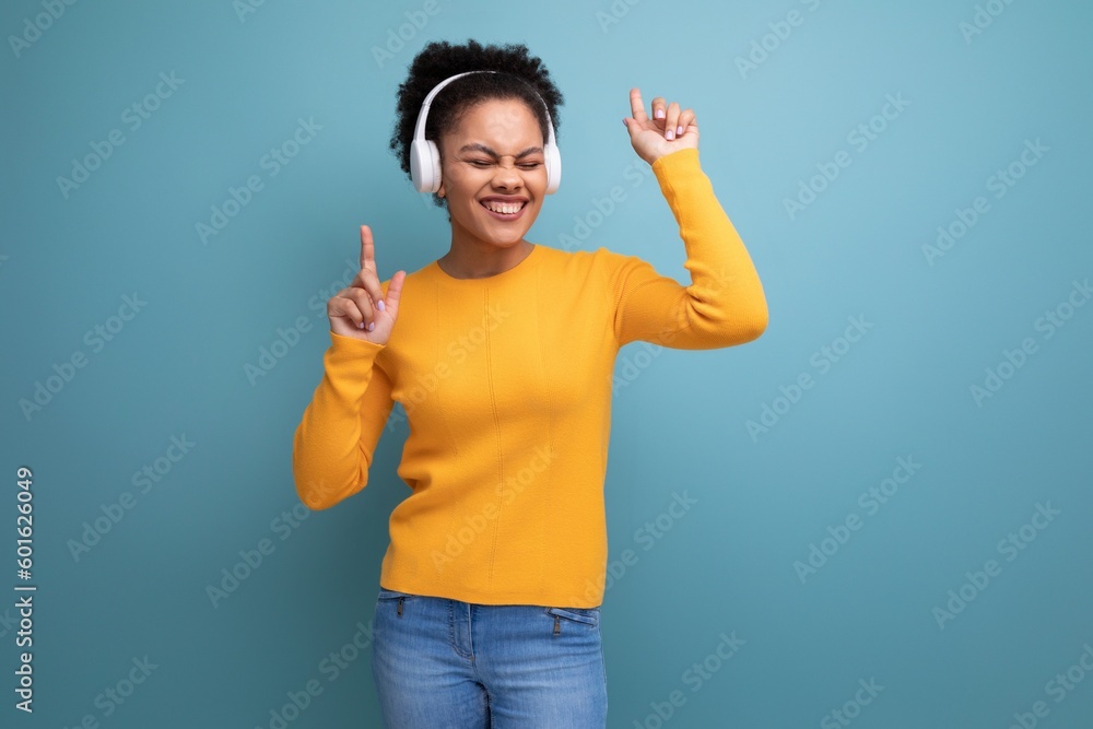 cheerful young hispanic business woman with black curly hair listening to music in white headphones cheerful young hispanic business woman with black curly hair listening to music in white headphones