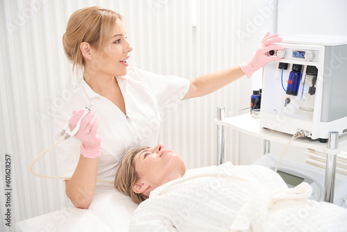 Pretty beautician adjusts CO2 laser for scar removal procedure