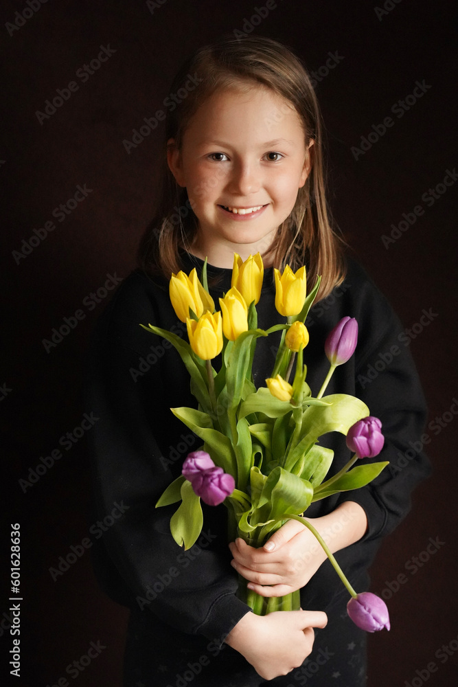 Attractive girl with a bouquet of tulips on a dark background, studio shot.
