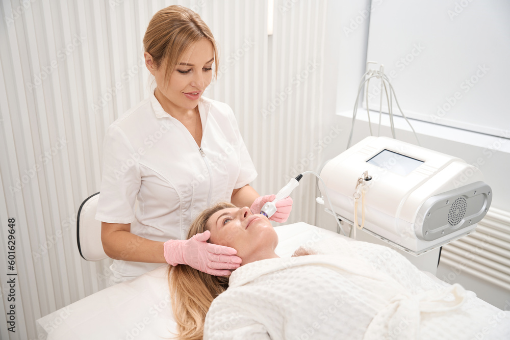 Young cosmetologist performs a non-surgical procedure radio wave face lifting Young cosmetologist performs a non-surgical procedure radio wave face lifting
