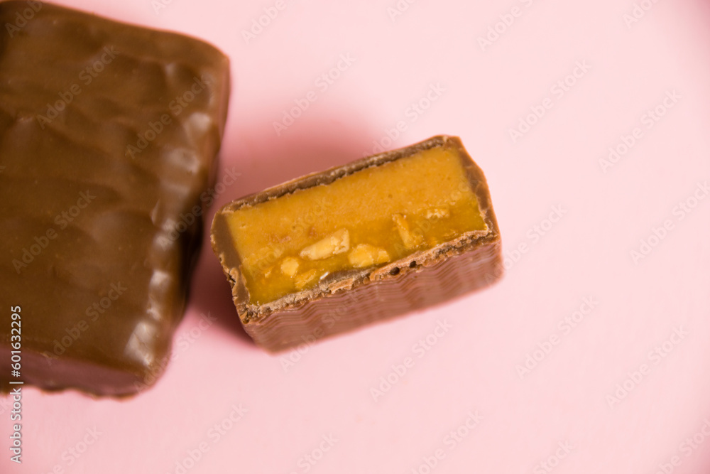 Flatlay, sweet chocolate bar with salted caramel macro on pink paper background with copy space Flatlay, sweet chocolate bar with salted caramel macro on pink paper background with copy space
