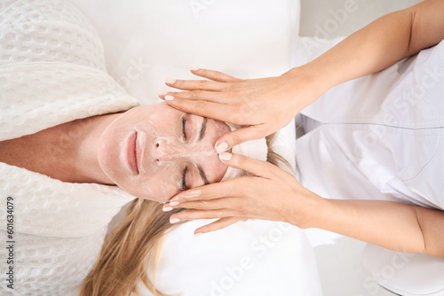 Professional cosmetologist applies a cleansing mask to a womans face