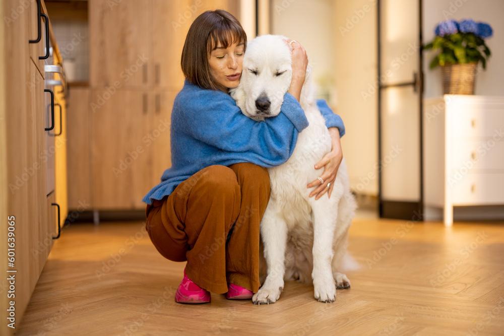 Portrait of young woman with her huge white dog, hugging together at home. Concept of domestic lifestyle and friendship with pets. Maremma shepherd dog Portrait of young woman with her huge white dog, hugging together at home. Concept of domestic lifestyle and friendship with pets. Maremma shepherd dog