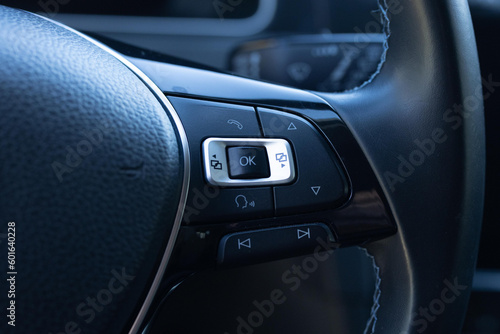 Buttons on the steering wheel to accept or reject calls from the phone. Hands free and media control buttons on the steering wheel in black leather modern car interior. Car detailing.