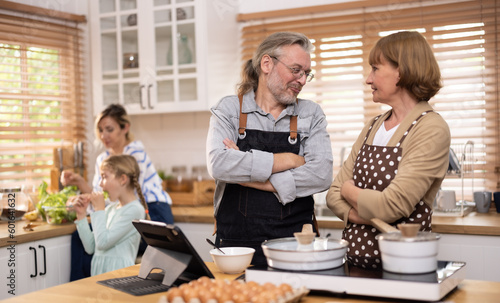 Multi-generational family members explore new and tasteful recipes on a tablet  make healthy food choices  cook  and enjoy meals together. Family gatherings help renew and strengthen relationships.