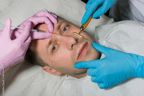 Handsome man receiving filler injection in beauty salon