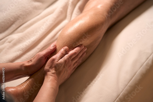 Professional spa therapist giving leg massage to male client