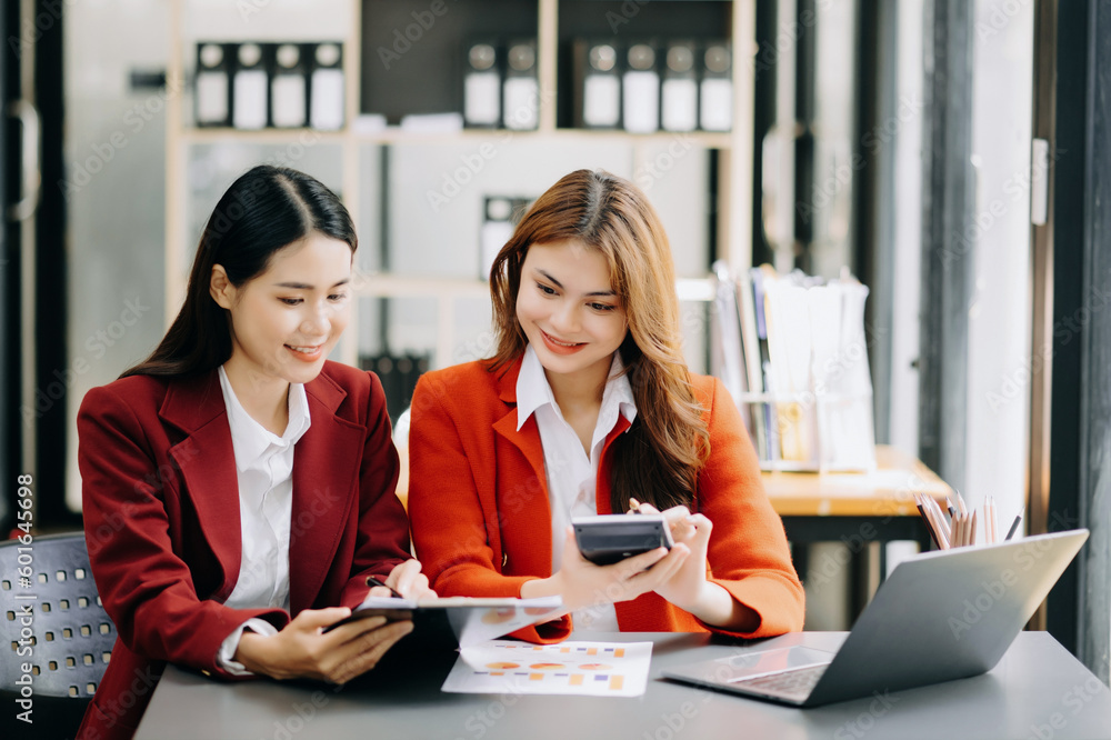 Two Asian businesswoman discuss investment project working and planning strategy with tablet laptop computer in office. Two Asian businesswoman discuss investment project working and planning strategy with tablet laptop computer in office.