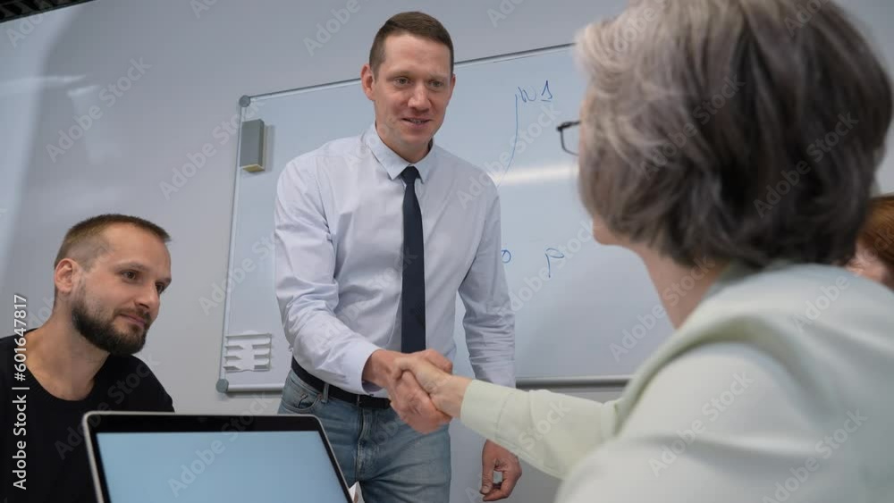 Caucasian man and mature woman shake hands after successful presentation. Caucasian man and mature woman shake hands after successful presentation.