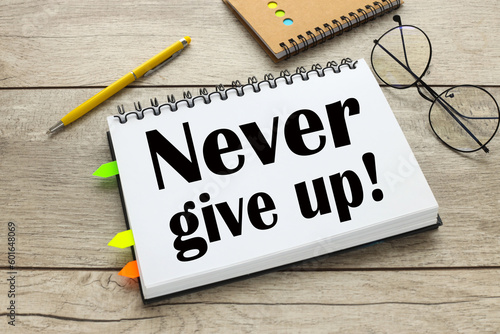 open notepad with stickers with the text Never give up on the table
