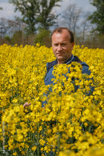 Agronomist man inspects rapeseed crops. Increasing yields and organic food production. Application of new technologies in agriculture.