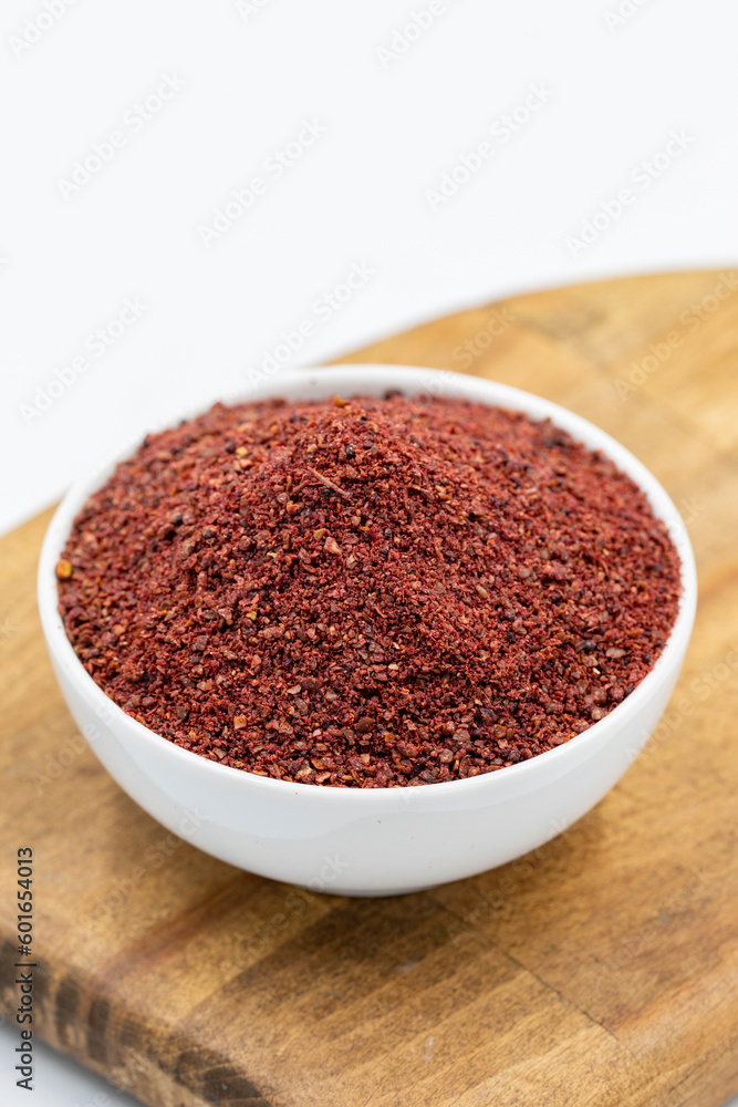 Sumac isolated on white background. Dried ground red Sumac powder spices in wooden bowl Sumac isolated on white background. Dried ground red Sumac powder spices in wooden bowl