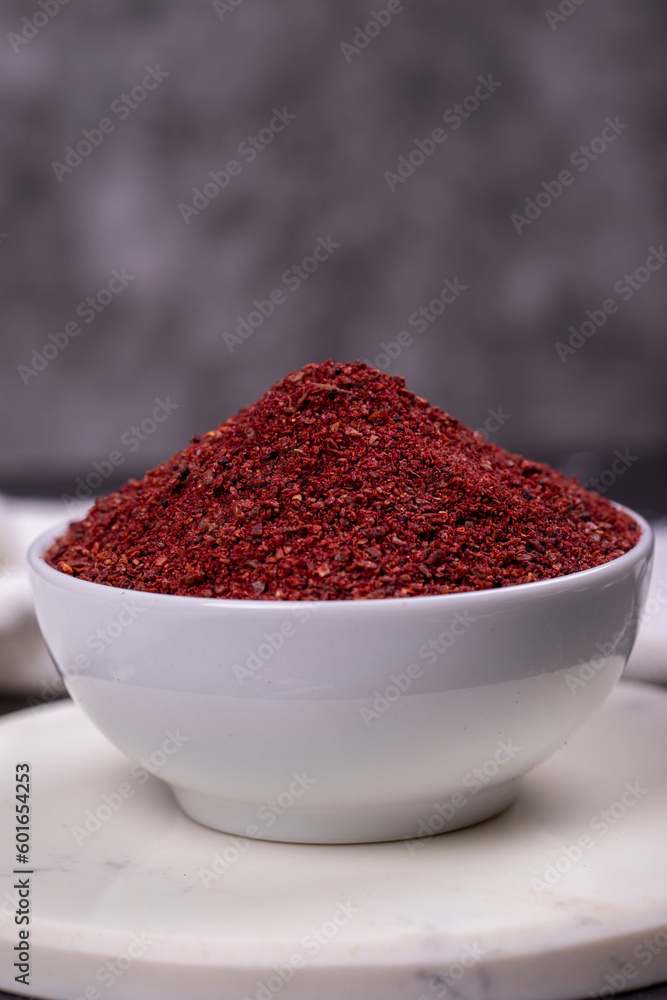 Sumac on dark background. Dried ground red Sumac powder spices in wooden bowl. Close up Sumac on dark background. Dried ground red Sumac powder spices in wooden bowl. Close up