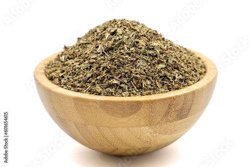Dried crushed basil isolated on white background. Dried ground basil powder spices in wooden bowl. Spice concept