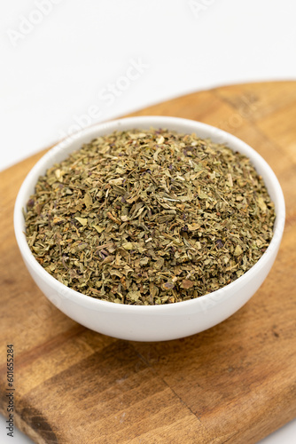 Dried crushed basil isolated on white background. Dried ground basil powder spices in ceramic bowl. Spice concept. Close up