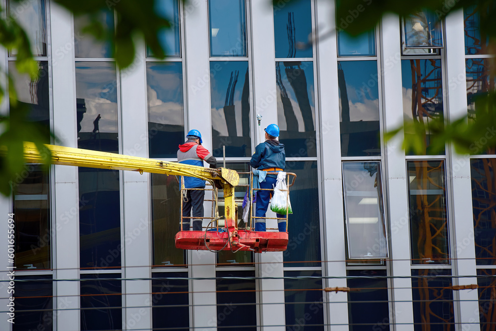 Window washing of highrise office building in crane bucket. Workers