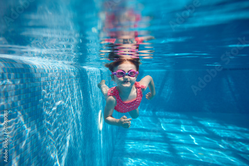Canvas Print Cute little baby girl, toddler in pink swimsuit diving, swimming underwater in swimming pool