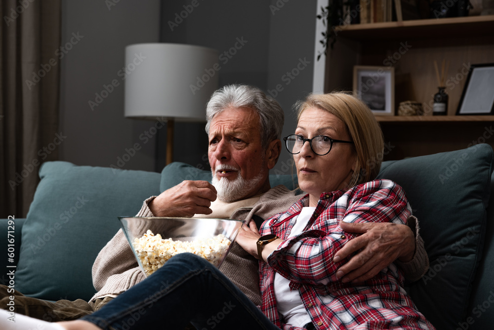 Mature married couple entertaining observing terrified TV program